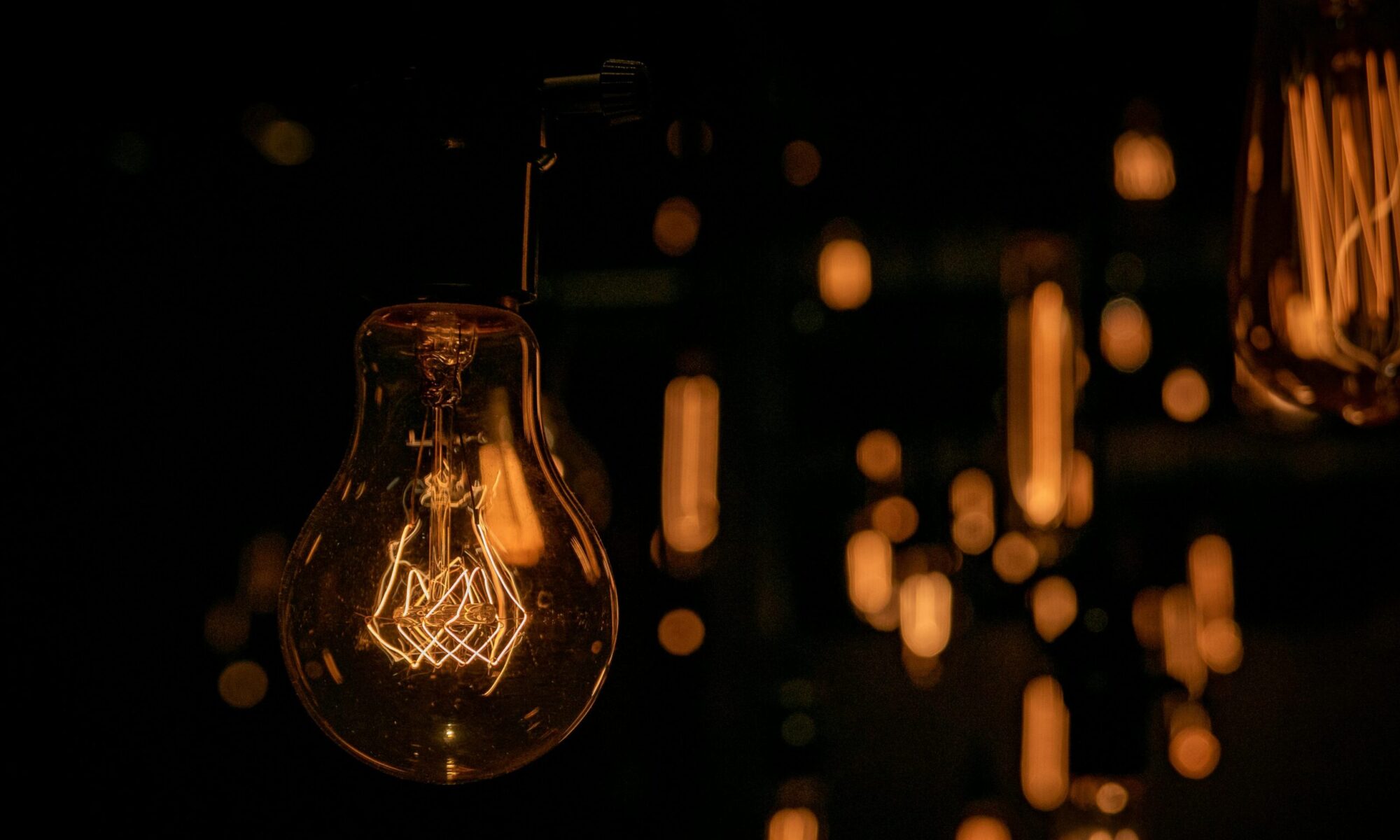 Warm glow of vintage light bulbs hanging in a dark setting, creating an inviting atmosphere.